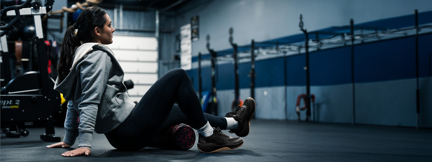 Person stretching with a foam roller in a gym setting